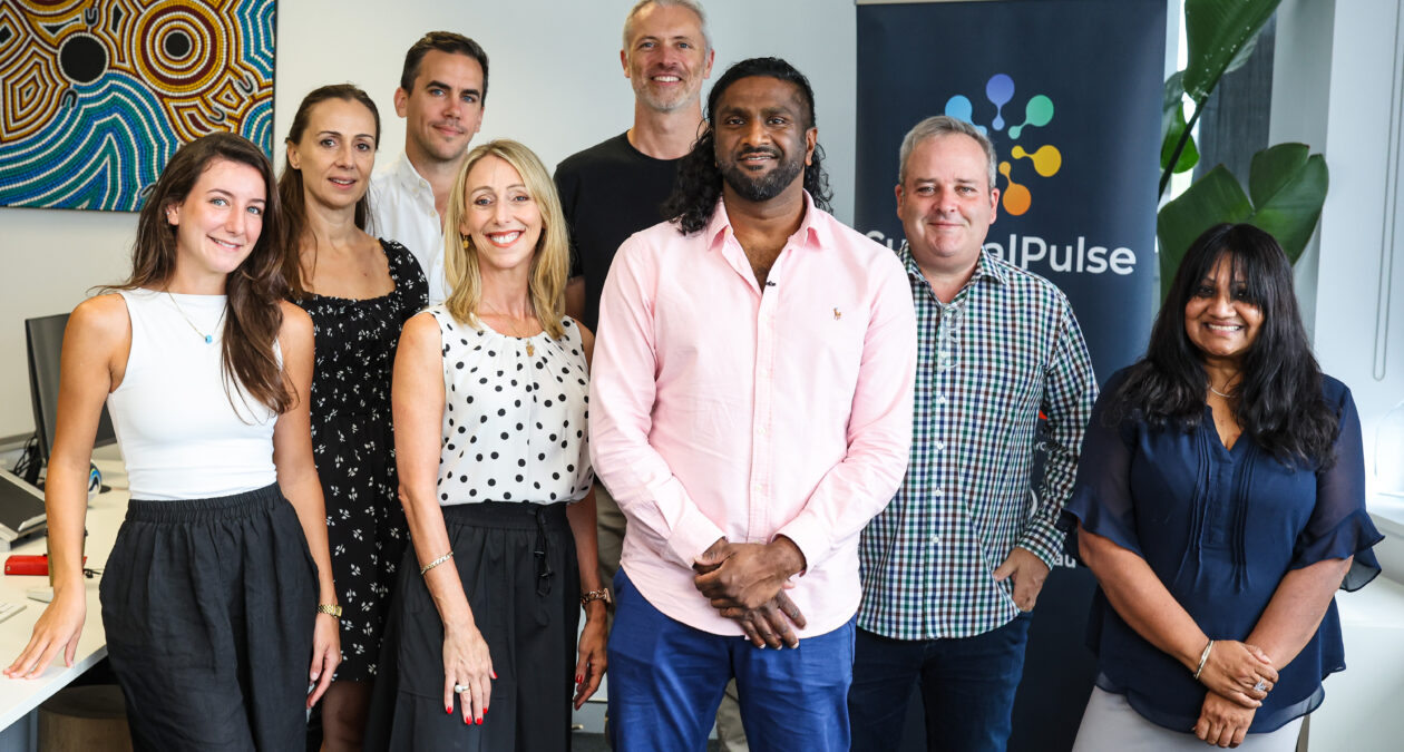 eight people smiling at the camera in an office