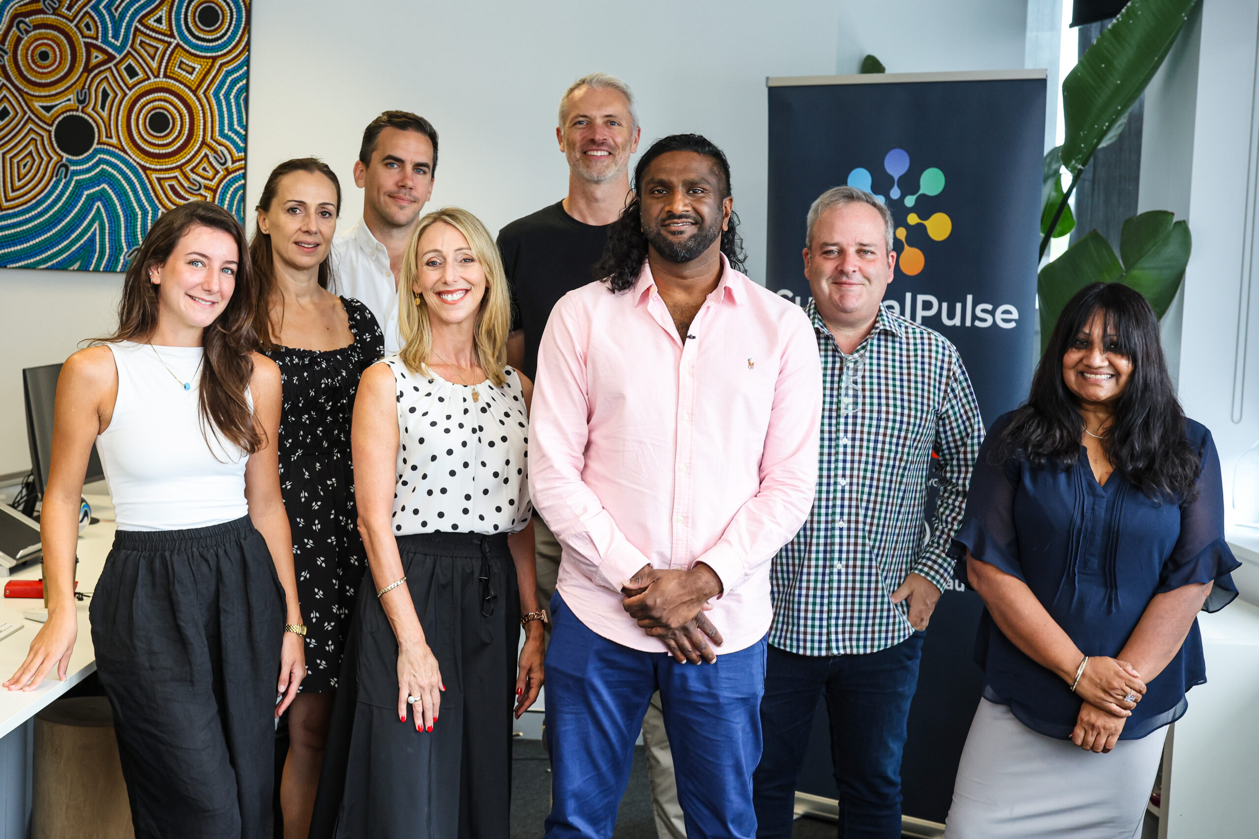 eight people smiling at the camera in an office