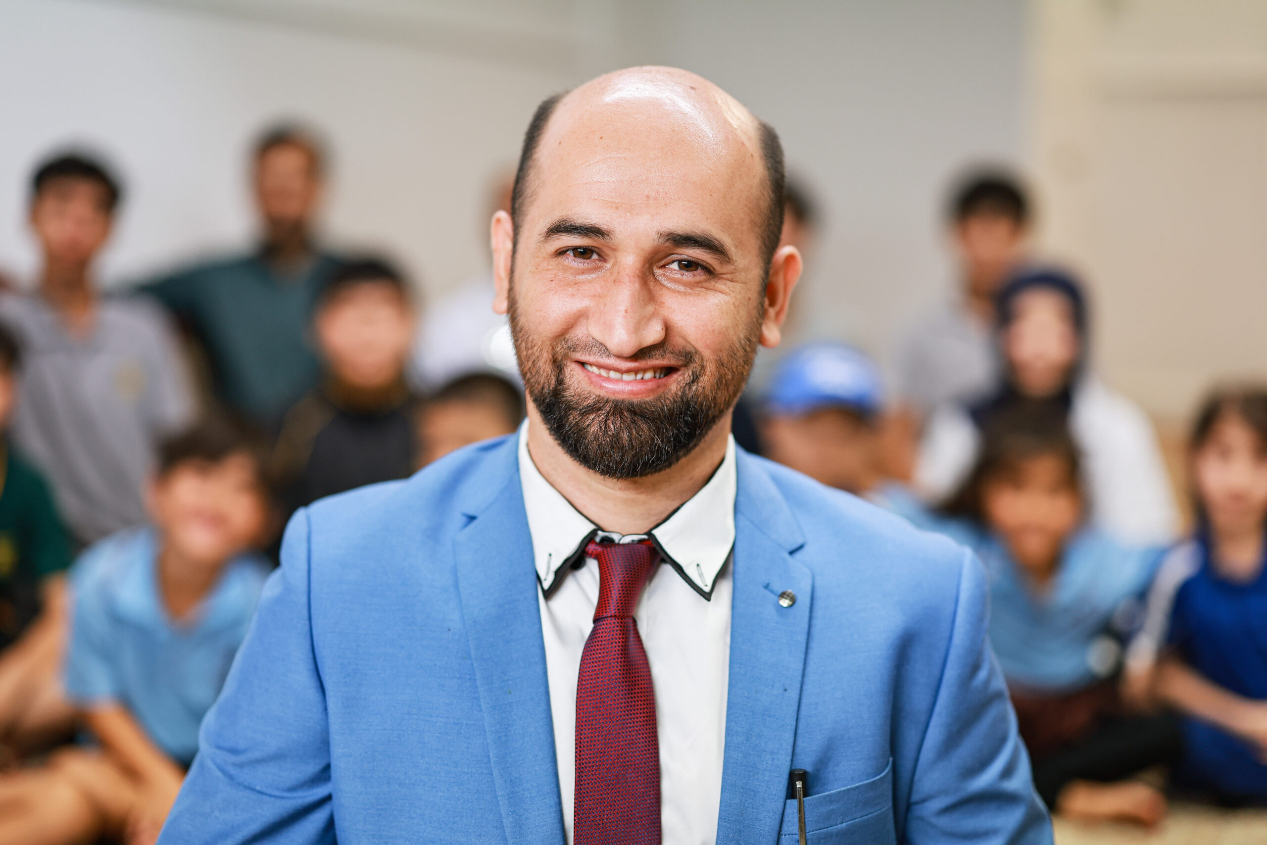 a man looking at the camera with students behind him