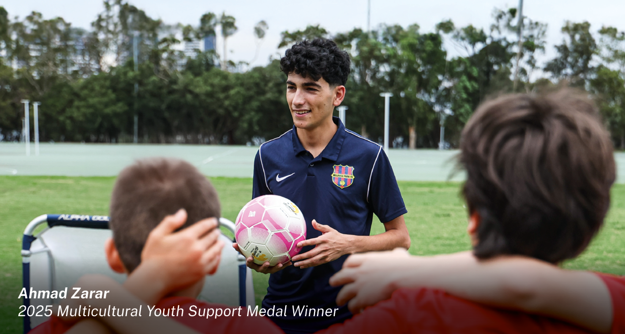 Young person holding a soccer ball on an oval