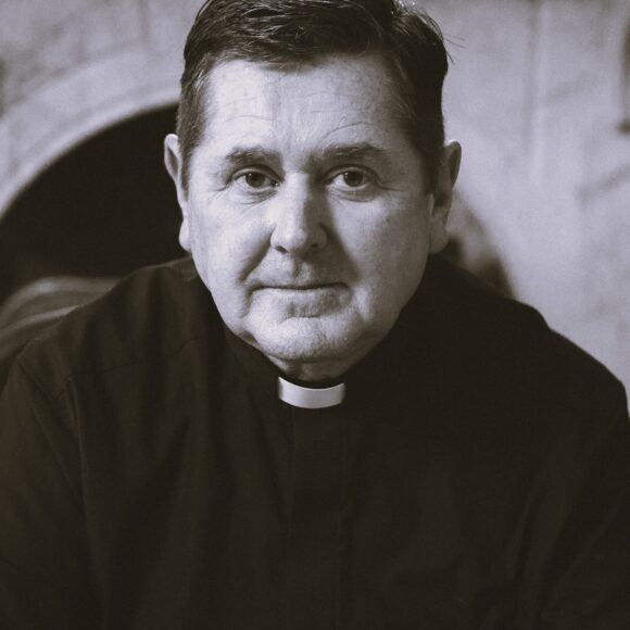 Warm black and white photo of Father Chris Riley.