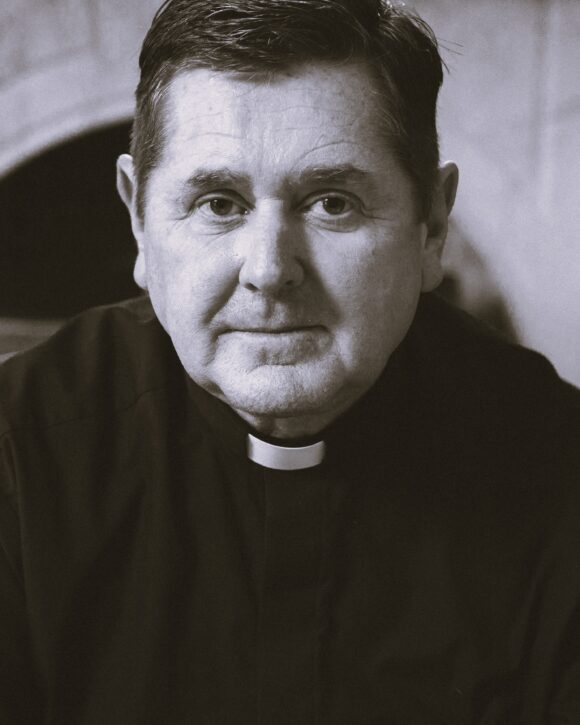 Warm black and white photo of Father Chris Riley.