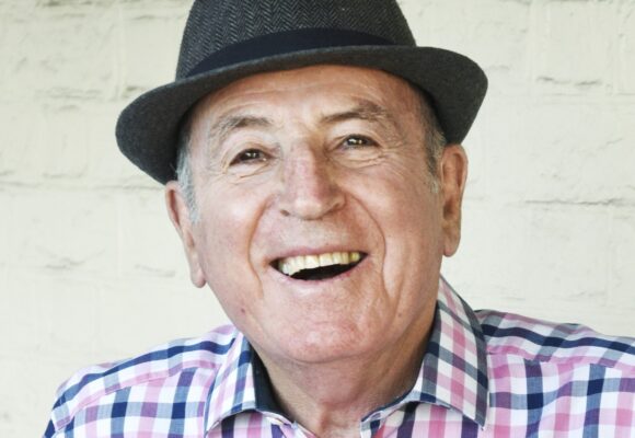 Colour portrait photo of George Bartolo, smiling and wearing a hat.