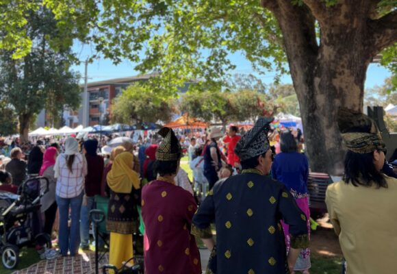 People at a festival in a park on a sunny day.