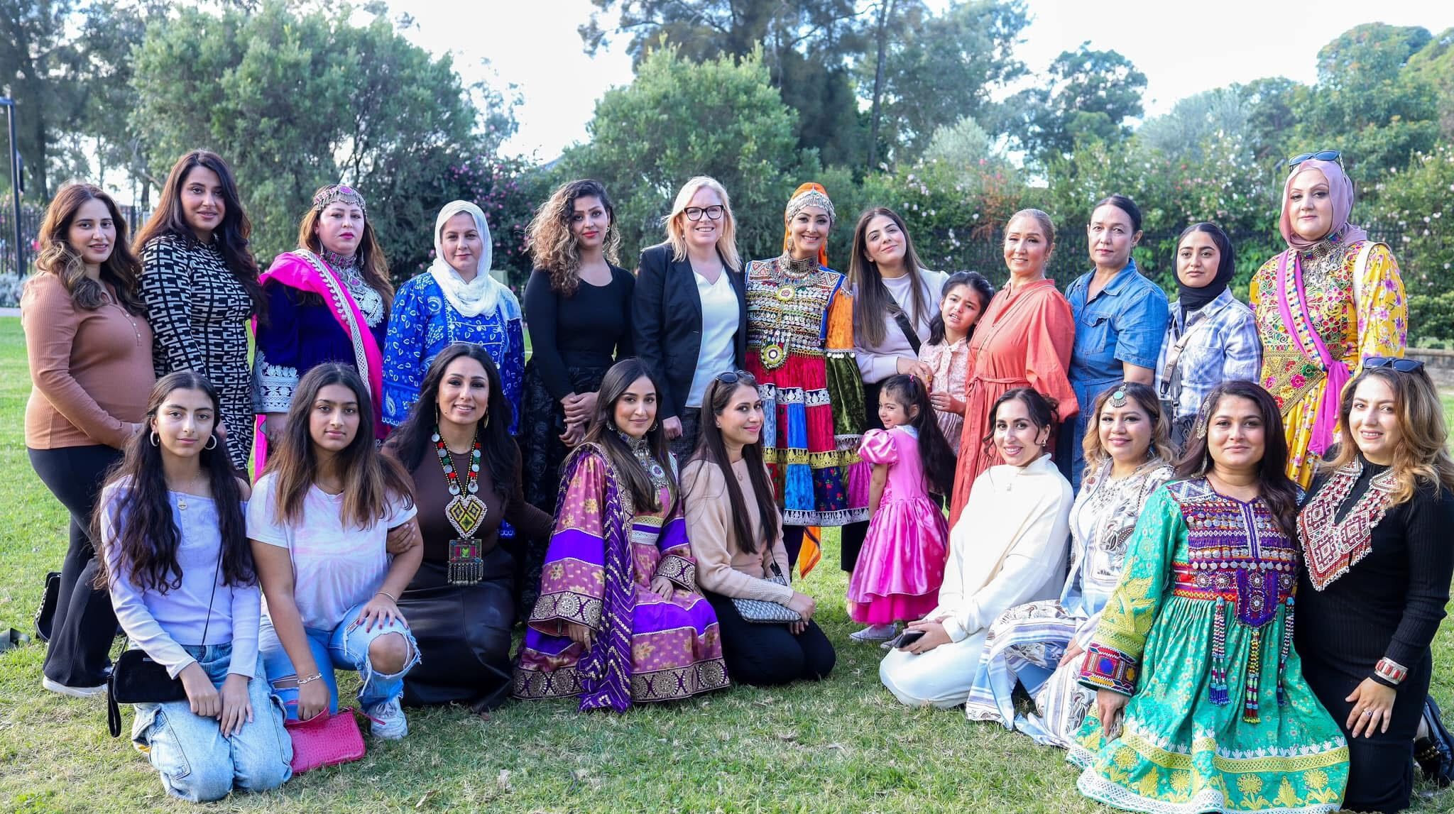 22 women and 2 children in a park looking at the camera.