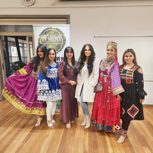 Six women in traditional dress in a hall.